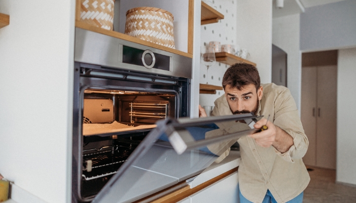 Serv_Urgent-Appliance-First-Aid_3.jpg Man double-checking the door seals on his oven