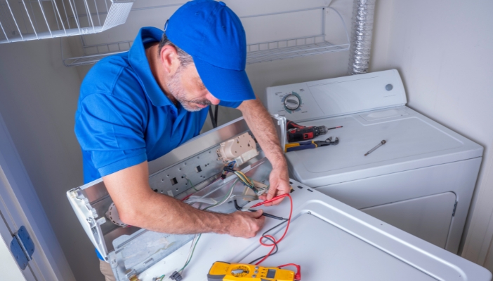 Serv_Urgent-Appliance-First-Aid_5.jpg An appliance technician fixing the electric components on a washer