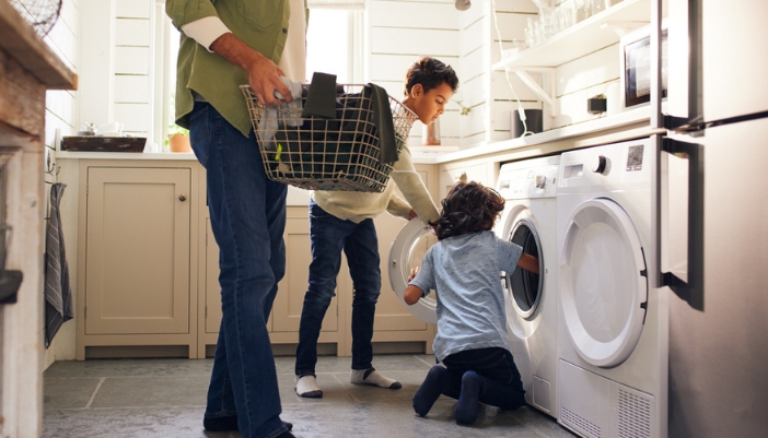 A family loads a washing machine at home.