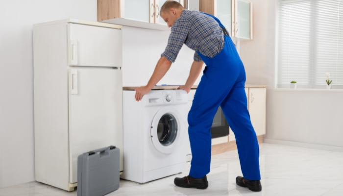 Service repairmen putting washing machine back after successful fix