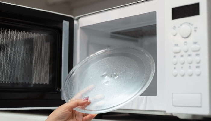 Closeup of someone pulling out the microwave plate