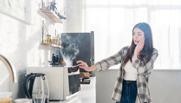 Alarmed woman turning off microwave after hearing weird noises and seeing smoke