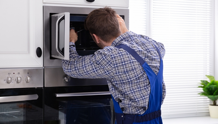 Service repairman fixing built-in microwave