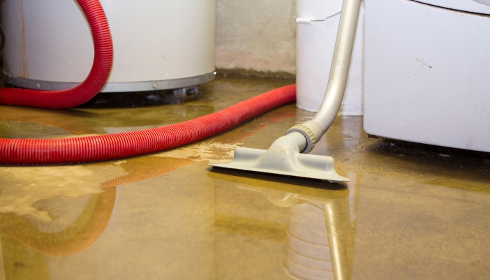 Closeup of a flooded basement with a washer in the background