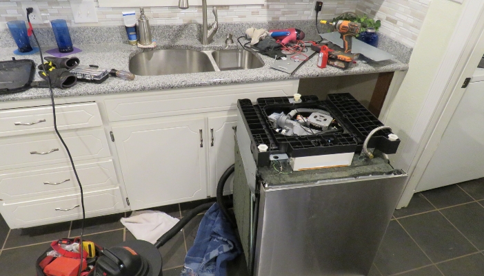 A dishwasher pulled out and disconnected from hoses
