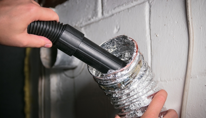 Closeup of someone vacuuming out the dryer vent hose