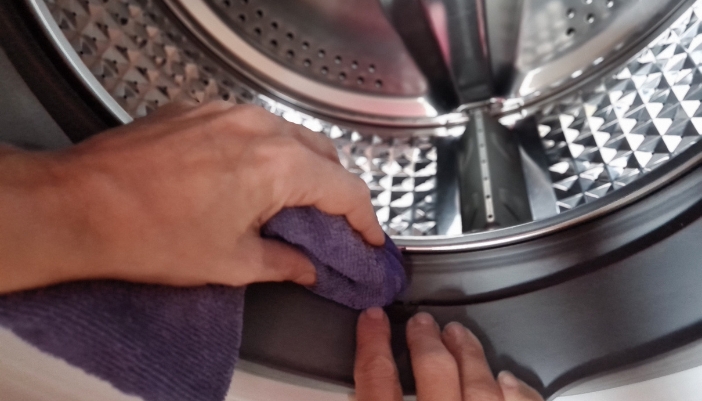 Closeup of someone wiping the door gasket after a washer