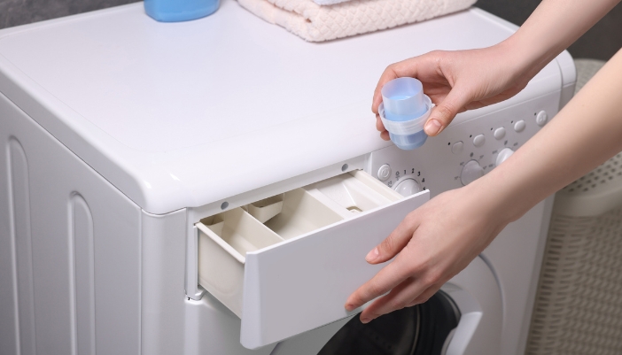 Closeup of someone adding detergent to their washer