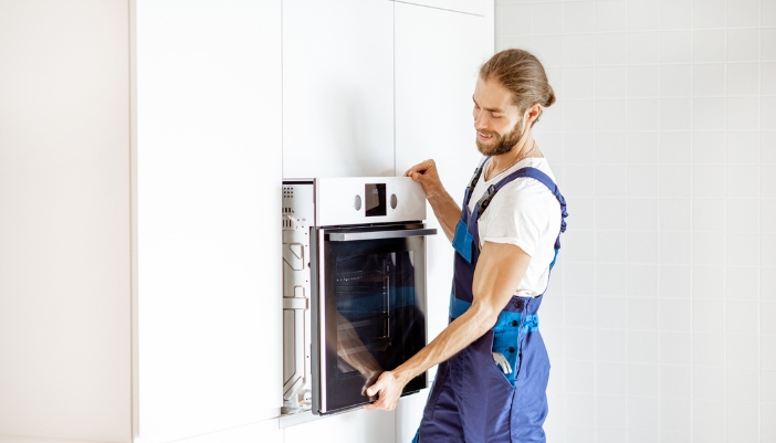 A service technician putting back an oven after fixing it