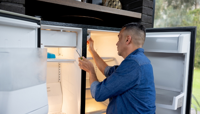 A repairman inspecting the temperature settings on a fridge