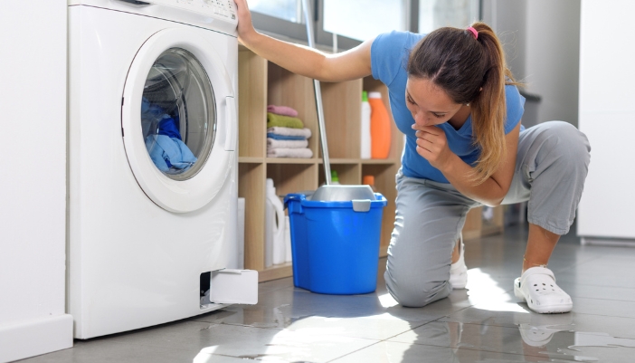 A woman inspecting her washer dryer combo leaking water