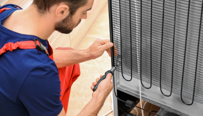 Maintenance repairman checking refrigerator coils