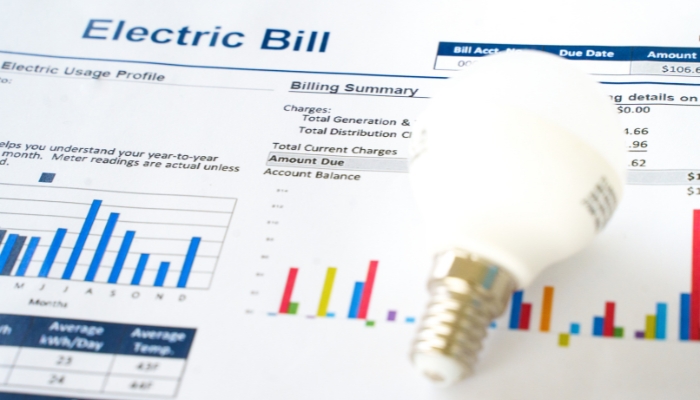 Closeup of a high energy bills and a light bulb on top of it