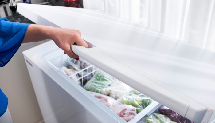 Closeup of hand opening a well-organized deep freezer
