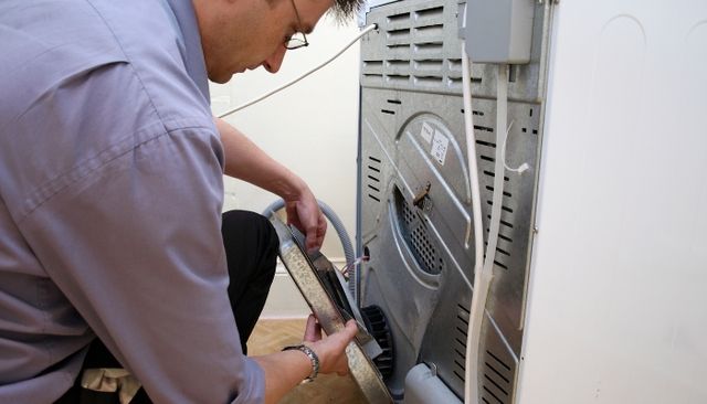 side view of a man opening the back of a dryer