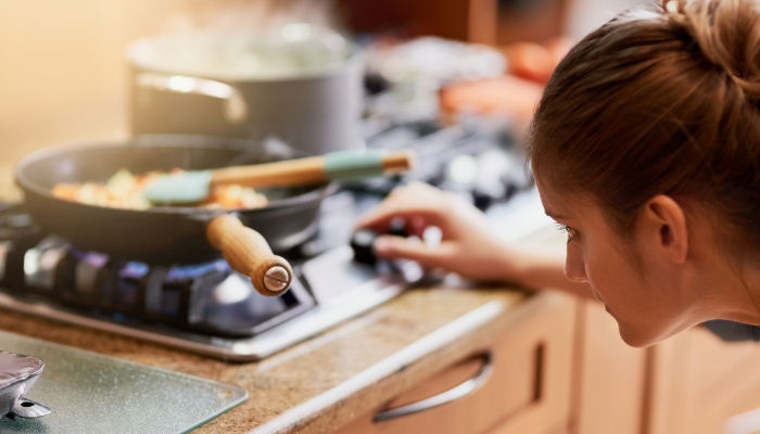 Serv_Gas-Burner-Troubleshooting_4.jpg Closeup of a woman adjusting the flame on her gas burner