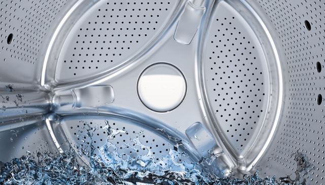 view of the inside of a top load washer drum with water splashing into it