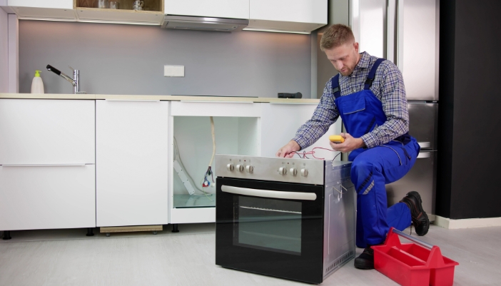 An appliance tech is calibrating an oven