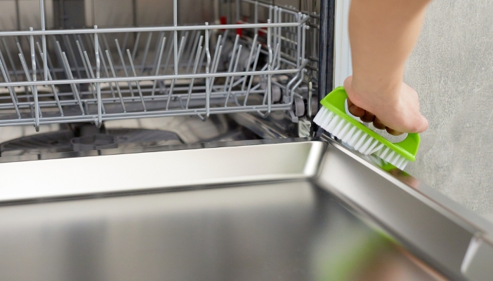 Closeup of someone deep cleaning the dishwasher