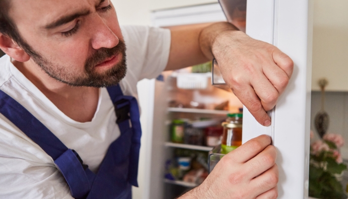 Closeup of a service tech inspecting the refrigerator door seal