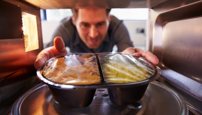 Interior closeup of a man placing food in a microwave