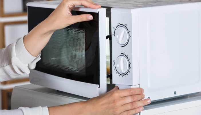 Closeup of someone having trouble opening the microwave door