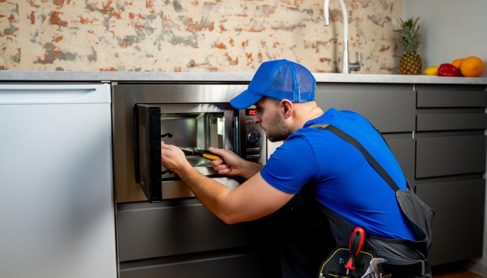 A service repairman working on a built-in microwave