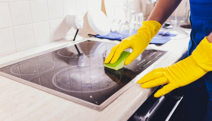 Closeup of someone cleaning a cooktop with a gentle cleaner