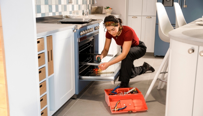 A woman DIY fixes her own broken stove at home.