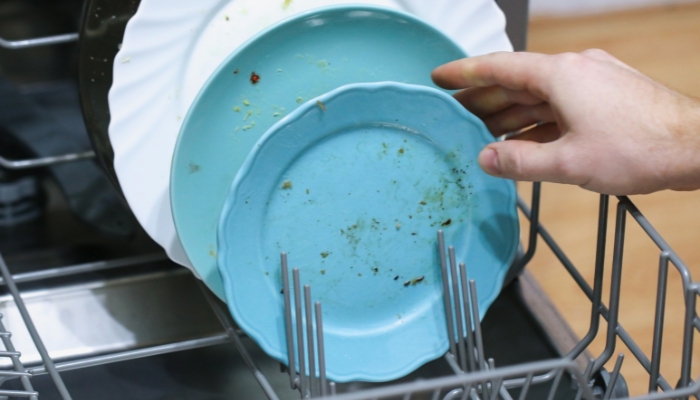 Serv_Appliance-Maintenance-Energy-Efficiency_2.jpg Closeup of someone placing un-rinsed dishes in the dishwasher