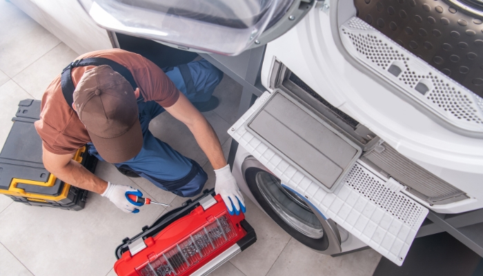 Serv_Appliance-Maintenance-Energy-Efficiency_3.jpg Service technician working on a stacked washer and dryer unit