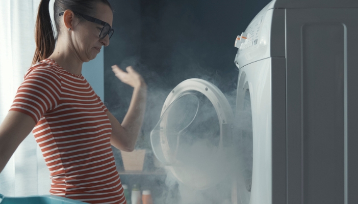 Woman waving away the smoke from her dryer that’s on fire