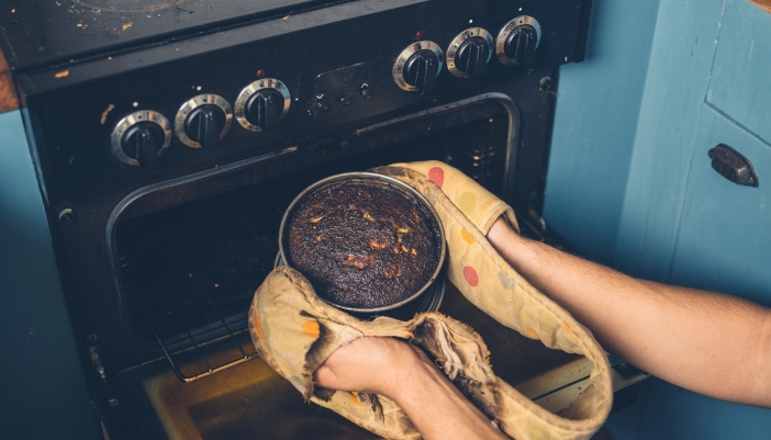 Closeup of someone pulling out a burnt dish from their range