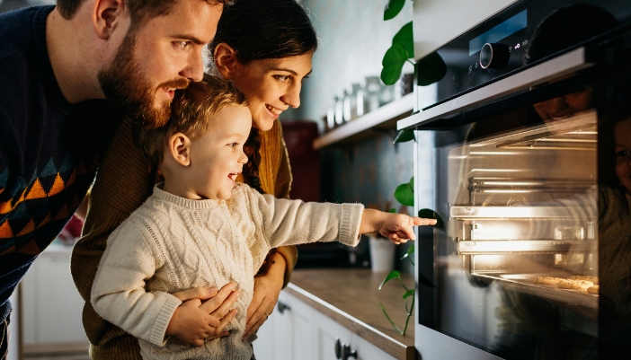 Family looking at the cookies baking in the oven with the light on
