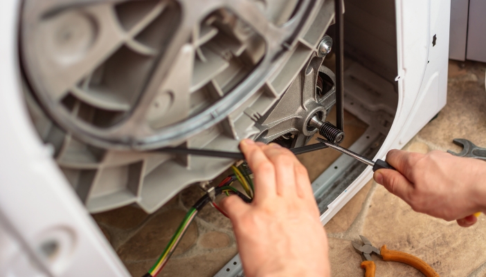 Serv_Off-Balance-Washer_3.jp Closeup of service repairmen working on the washing machine bearings