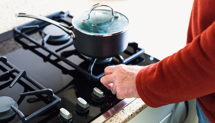 Closeup of hand trying to turn a burner on the cooktop