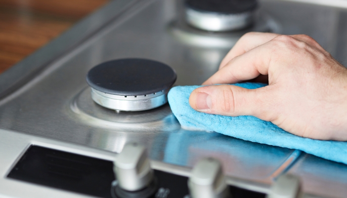 Closeup of someone cleaning the burners on their gas cooktop