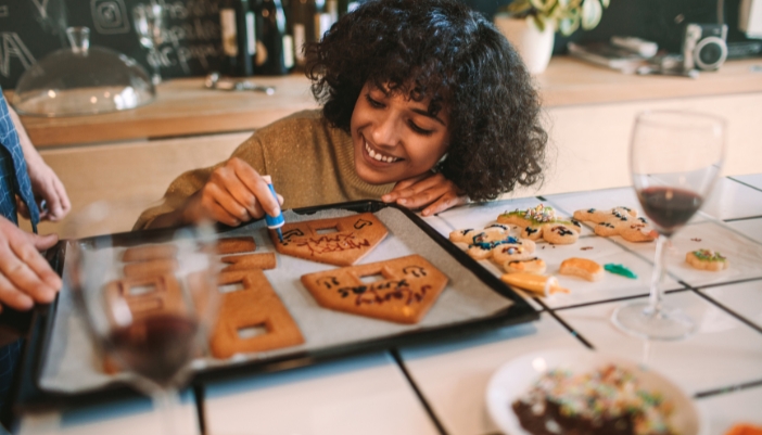 Closeup of someone happily decorating gingerbread house fresh from the oven