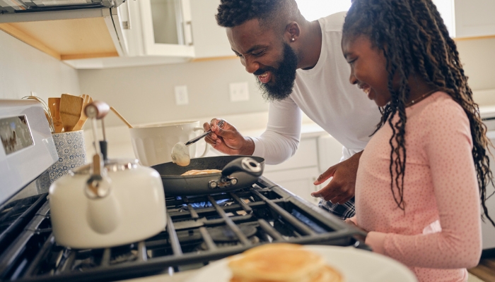 Father and daughter cooking something on their range