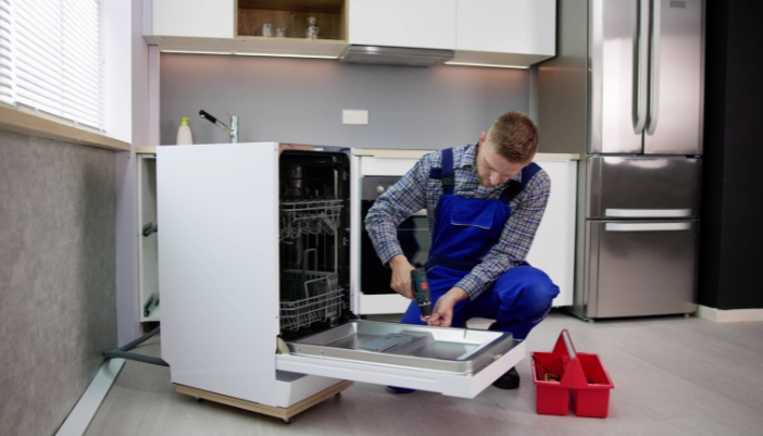 A professional appliance tech fixing a dishwasher