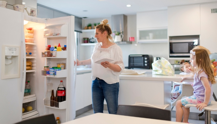 A family putting groceries in their fridge which has a water and ice dispenser