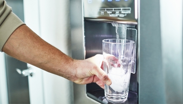 Closeup of someone grabbing fresh, clean water from their fridge