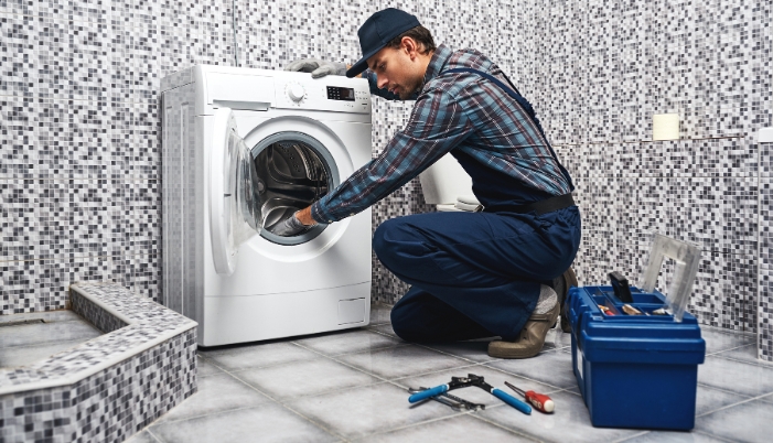 An appliance repairman fixing a washer