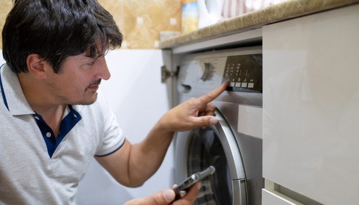 Serv_Washing-Machine-Control-Panel-Issues_3.jpg Frustrated man pressing the buttons again on his machine