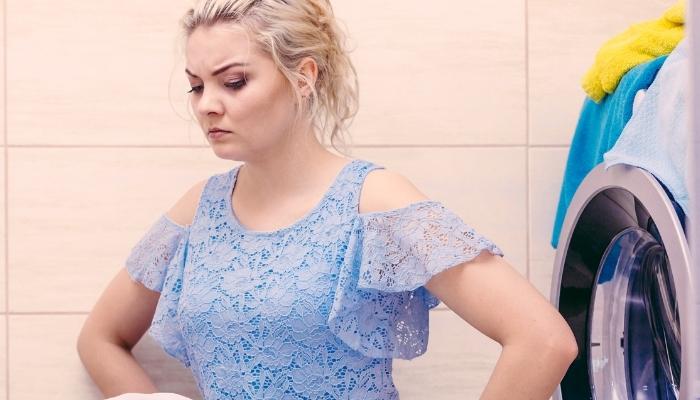 Woman looking down, upset that washer keeps stopping