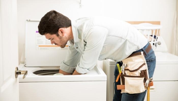 technician inspecting and fixing a dryer