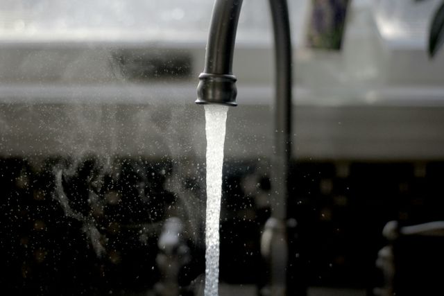 Close view of hot water coming out of a black luxury faucet