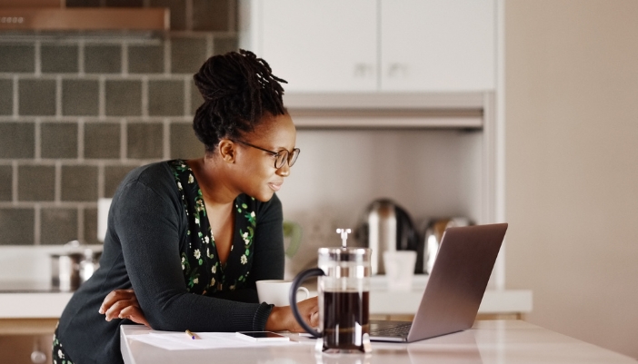 Woman researching on laptop in kitchen