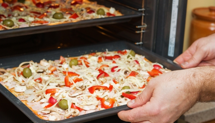 Multiple flat-bread pizzas going into oven