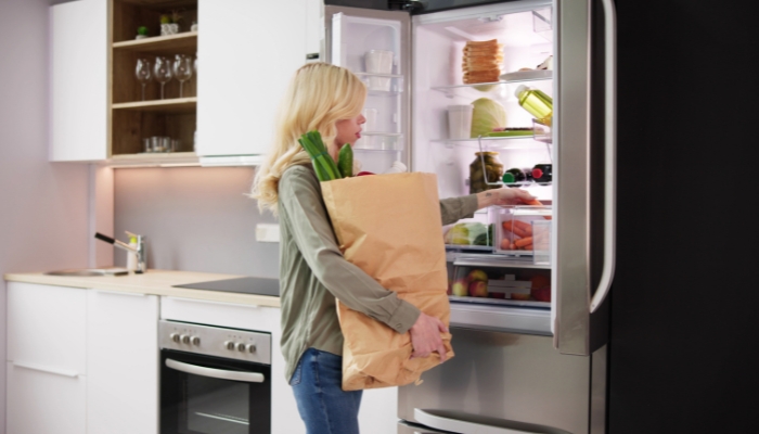 B0018_Counter-Depth-Refrigerators_1.jpg Woman putting groceries away into her counter-depth refrigerator